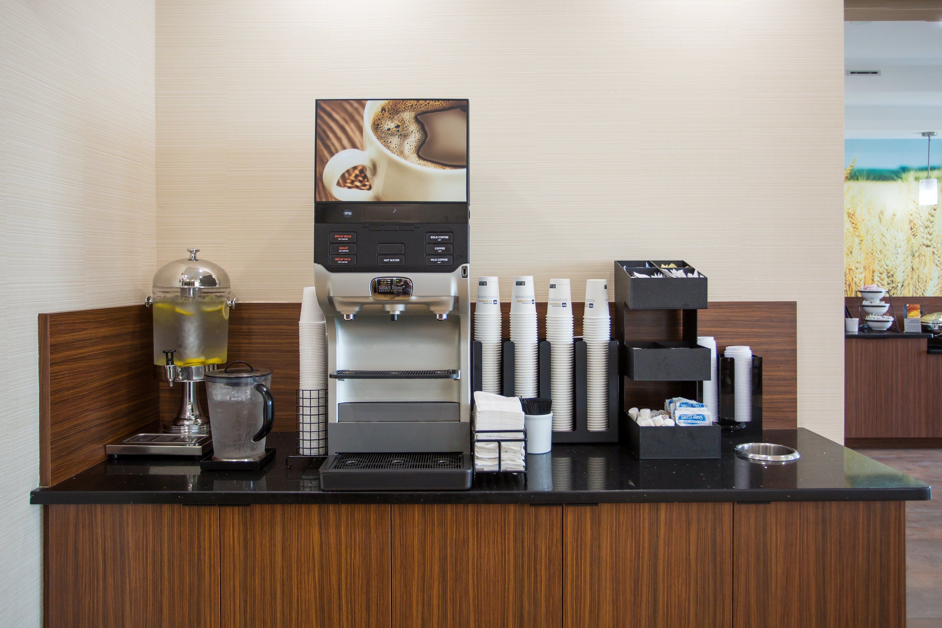 A coffee station with a coffee machine, a water dispenser, and a menu display.