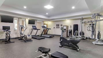Un gimnasio con cintas de correr, elípticas y equipo de pesas.