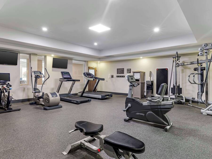 Un gimnasio con cintas de correr, elípticas y equipo de pesas.