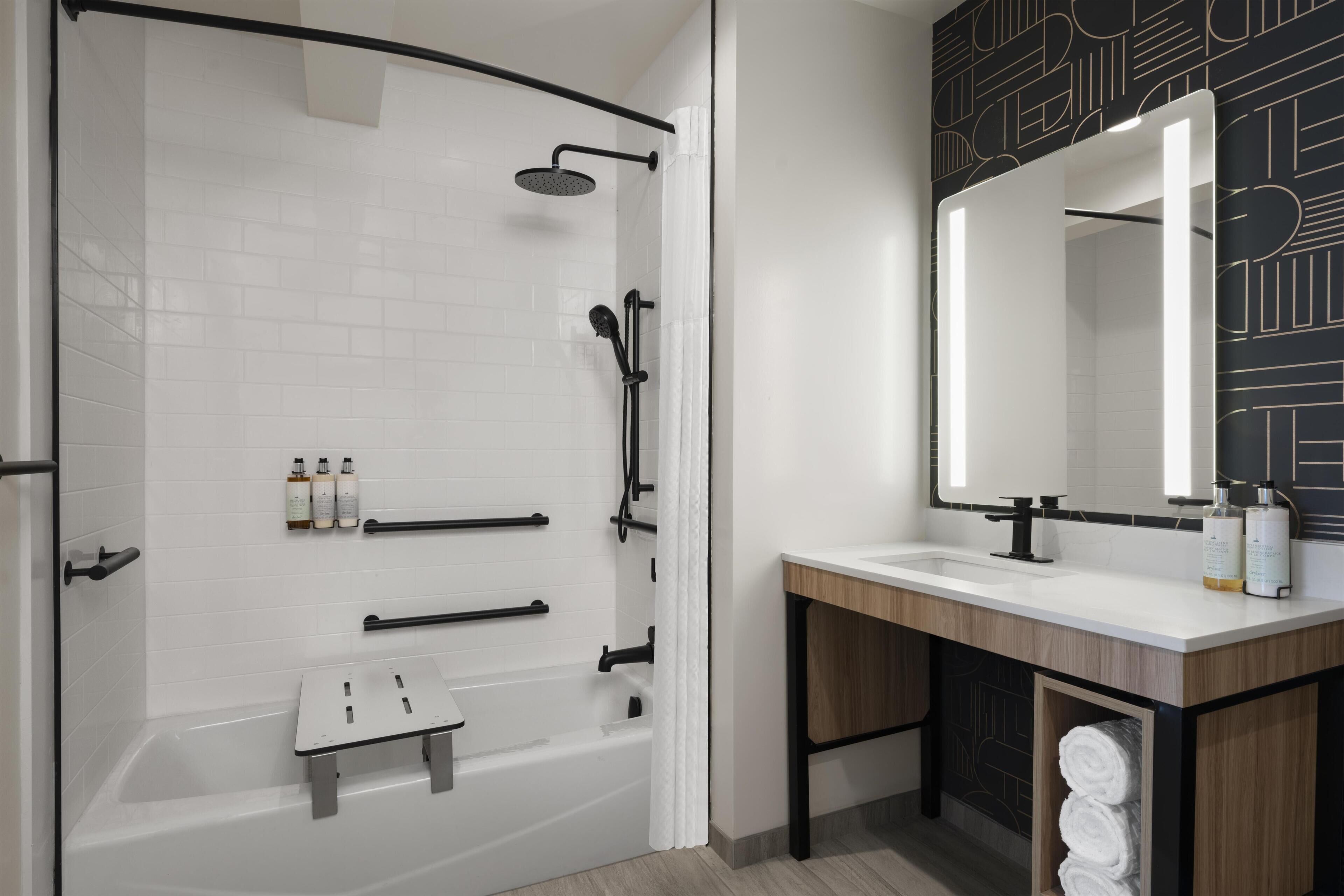 A modern bathroom with a shower, a vanity with a mirror, and a towel rack.