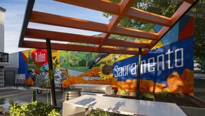 An outdoor seating area with a mural, a table, and a bench.