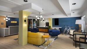 A modern hotel lobby with a reception desk, seating area, and a bar.
