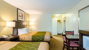 A hotel room with two beds, a desk, a chair, and a mirror.
