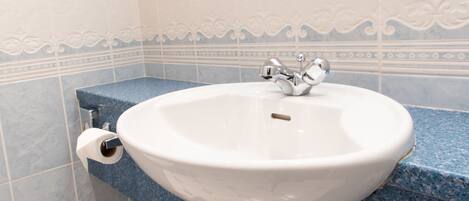 A bathroom with a white sink, blue countertop, and decorative wall tiles.