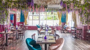 Een restaurant met tafels en stoelen, hangende planten en een kroonluchter.