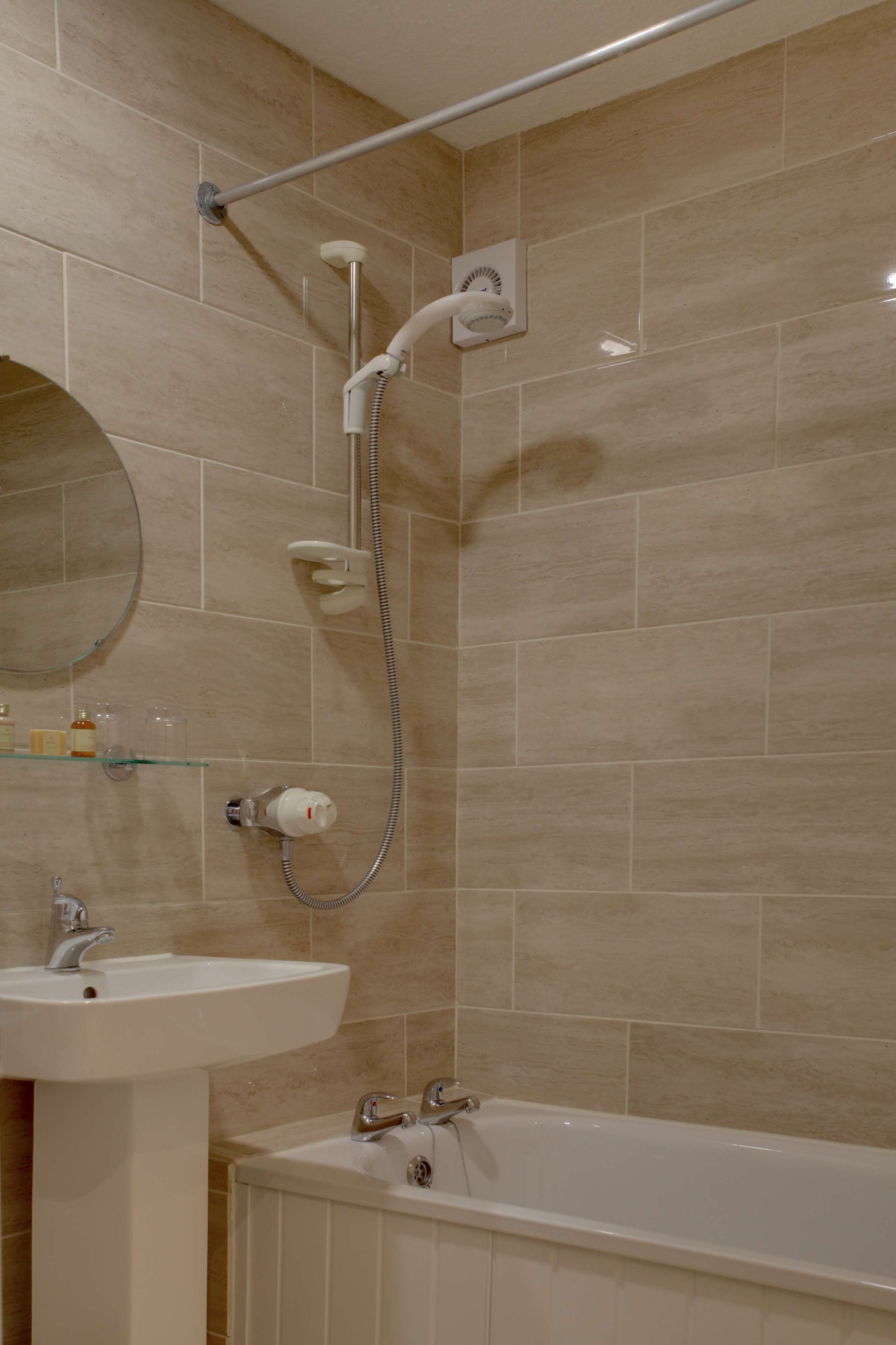 A bathroom with a bathtub, a sink, and a shower with a handheld showerhead.