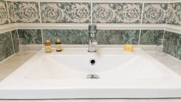A bathroom with a large sink, a mirror, and decorative tiles.