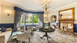 Een ruime woonkamer met een groot raam, een kroonluchter en een open haard.