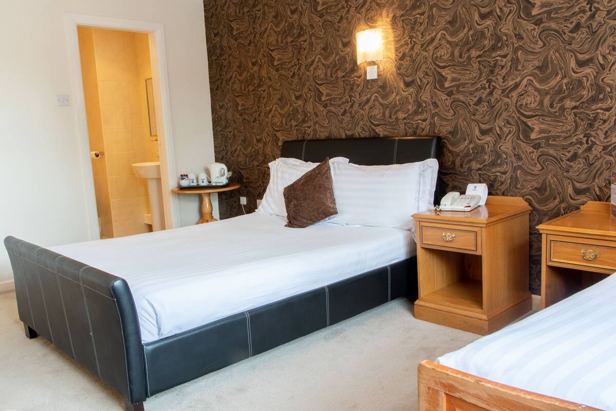 Une chambre d’hôtel avec un grand lit, une table de chevet avec un téléphone et une petite table de nuit.