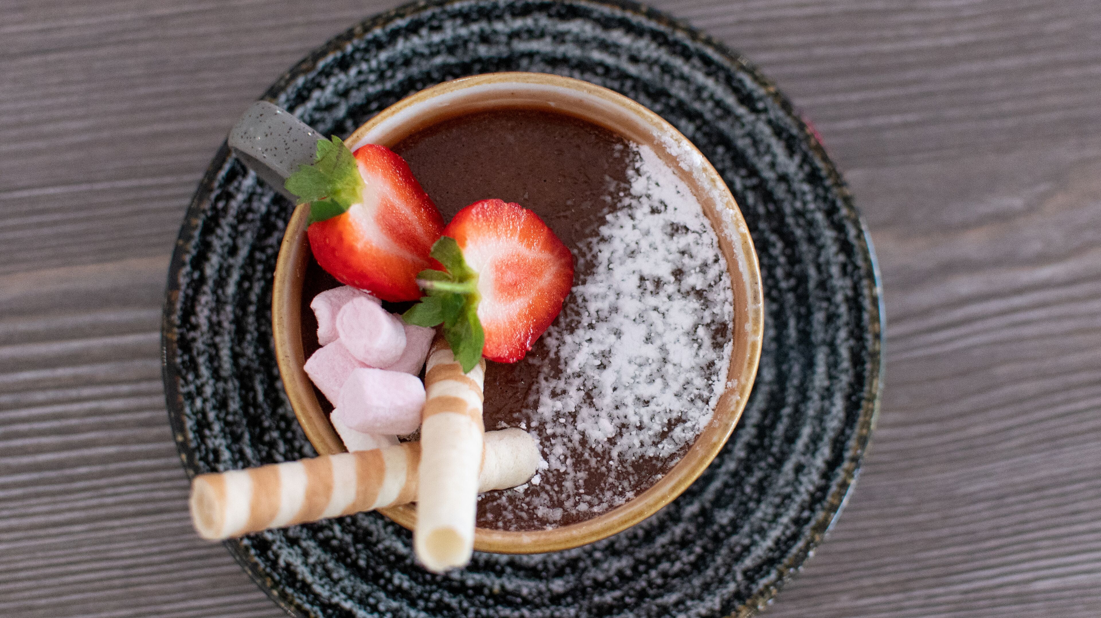 Een nagerecht met aardbeien en marshmallows op een bord.