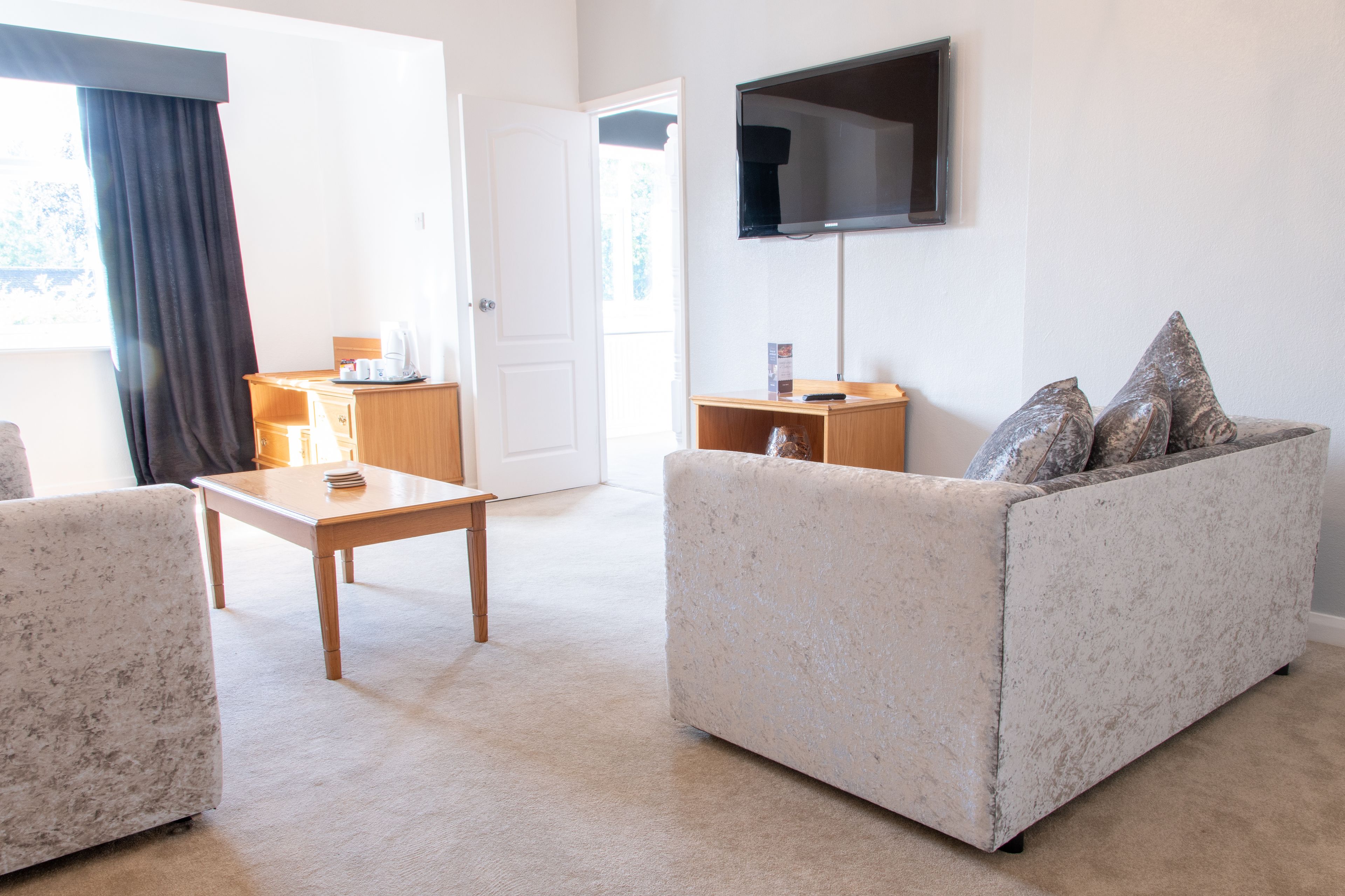 Ein Wohnzimmer mit einer Couch, einem Couchtisch und einem an der Wand befestigten Fernseher.
