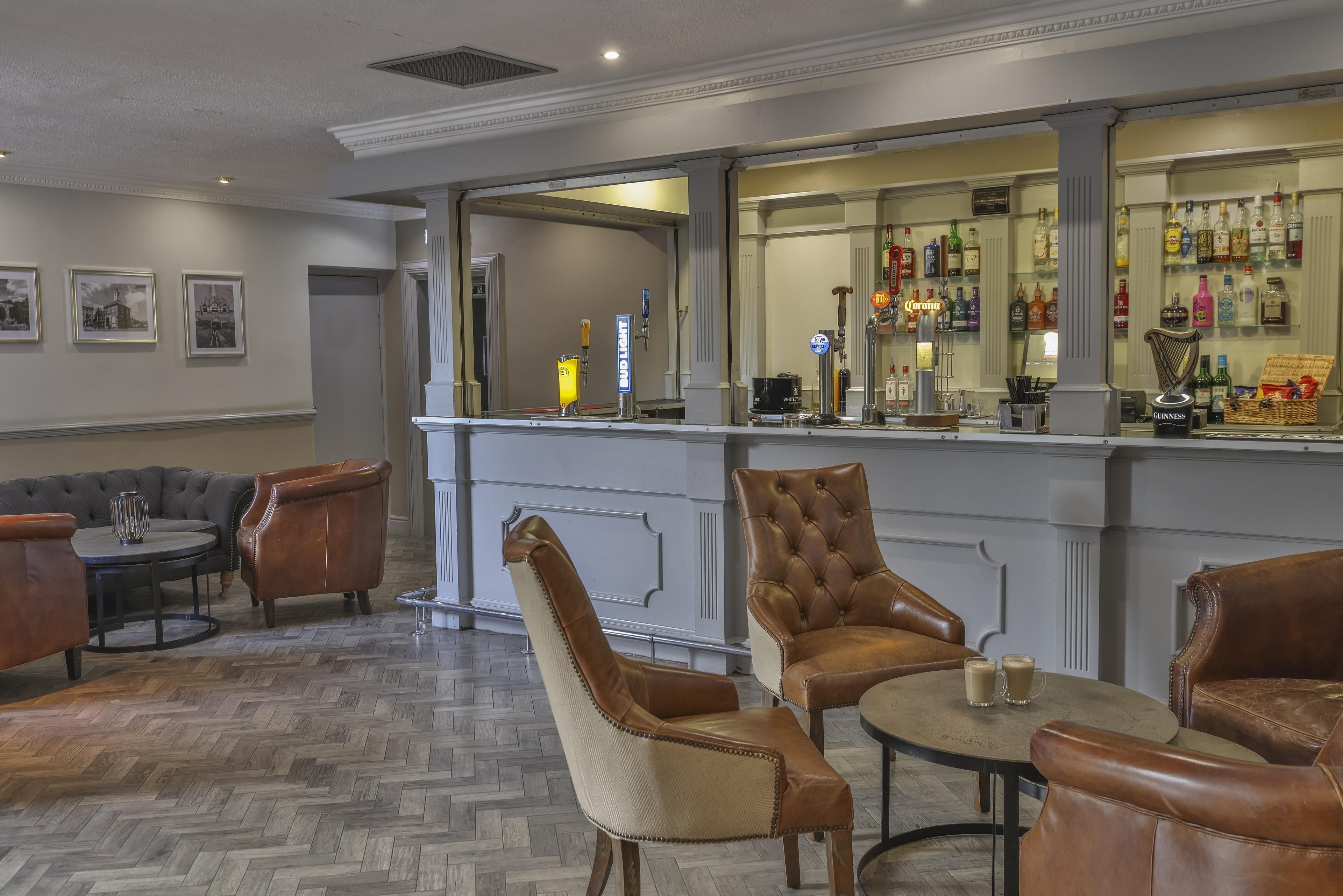 A bar area with leather chairs and a herringbone floor pattern.