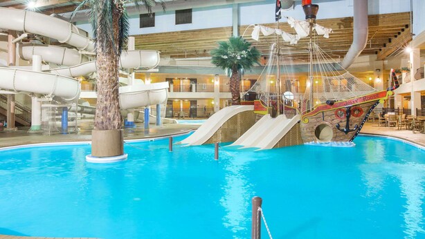 An indoor pool with slides and a ship-themed play area. - Ramada Tropics Resort & Conf Center by Wyndham Des Moines (Urbandale)