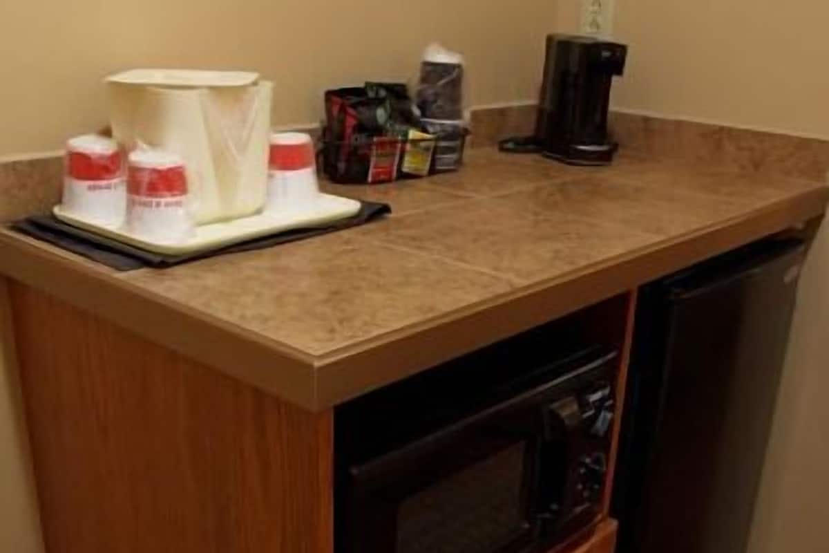 A compact kitchen with a microwave, a coffee maker, and a small cabinet.