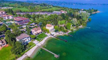 An aerial view of a lakeside property with multiple buildings, a dock, and a well-maintained lawn.