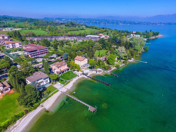 An aerial view of a lakeside property with multiple buildings, a dock, and a well-maintained lawn.