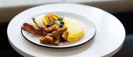 A plate of food with eggs, bacon, and fruit on a white plate.