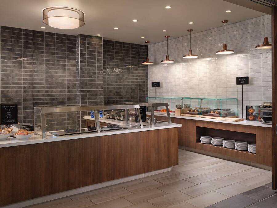 A modern breakfast area with a counter, display cases, and hanging pendant lights.