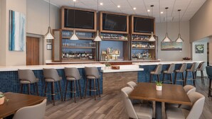 A modern bar area with high stools, a long counter, and a mix of bar stools and dining chairs.