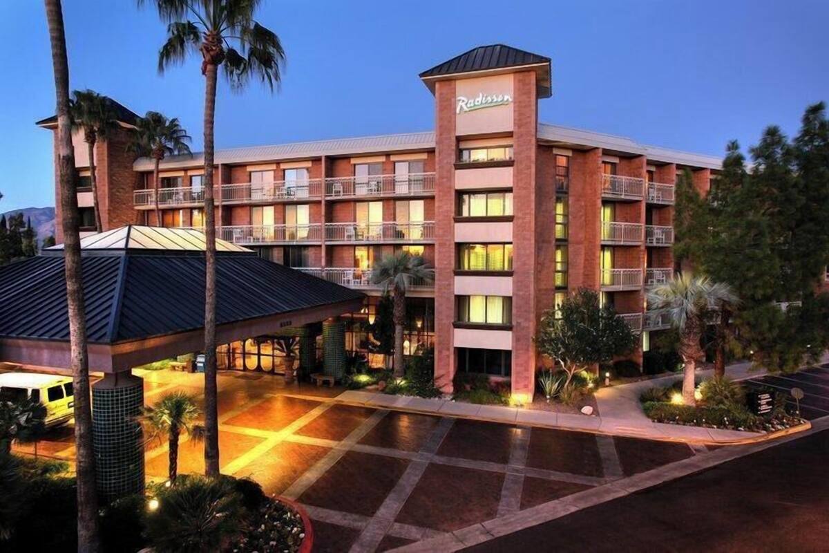 A Radisson hotel with a multi-story structure, outdoor covered parking, and palm trees.