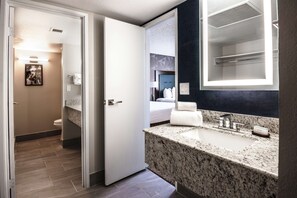 A modern bathroom with a granite countertop, a large mirror, and a separate toilet area. - Embassy Suites by Hilton Tucson East (Tucson)