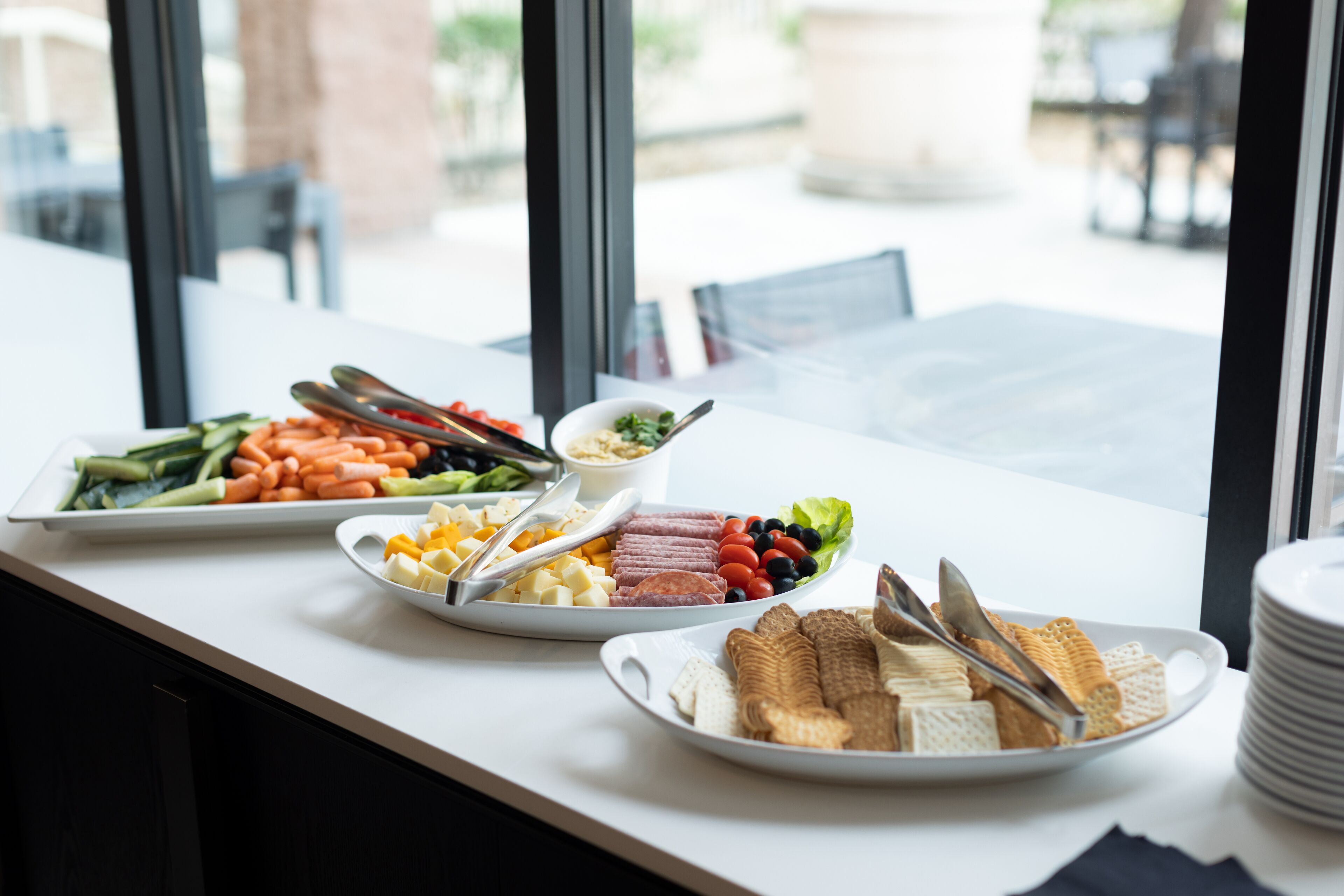 A buffet table with various food items including vegetables, cheeses, meats, and crackers.