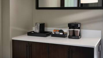 A modern bathroom with a white countertop, a black coffee maker, and a Cuisinart espresso machine.