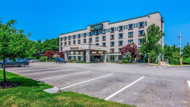 A Quality Inn hotel with a large parking lot and a clear blue sky.