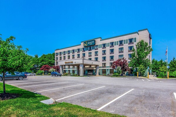 A Quality Inn hotel with a large parking lot and a clear blue sky.