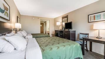 A hotel room with a large bed, a desk, a chair, a television, and a mirror.