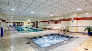 Een zwembadgedeelte van een hotel met een jacuzzi, ligbedden en een betegelde vloer.