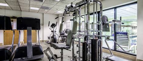 Un gimnasio con cintas de correr, máquinas de pesas y equipo de ejercicio.