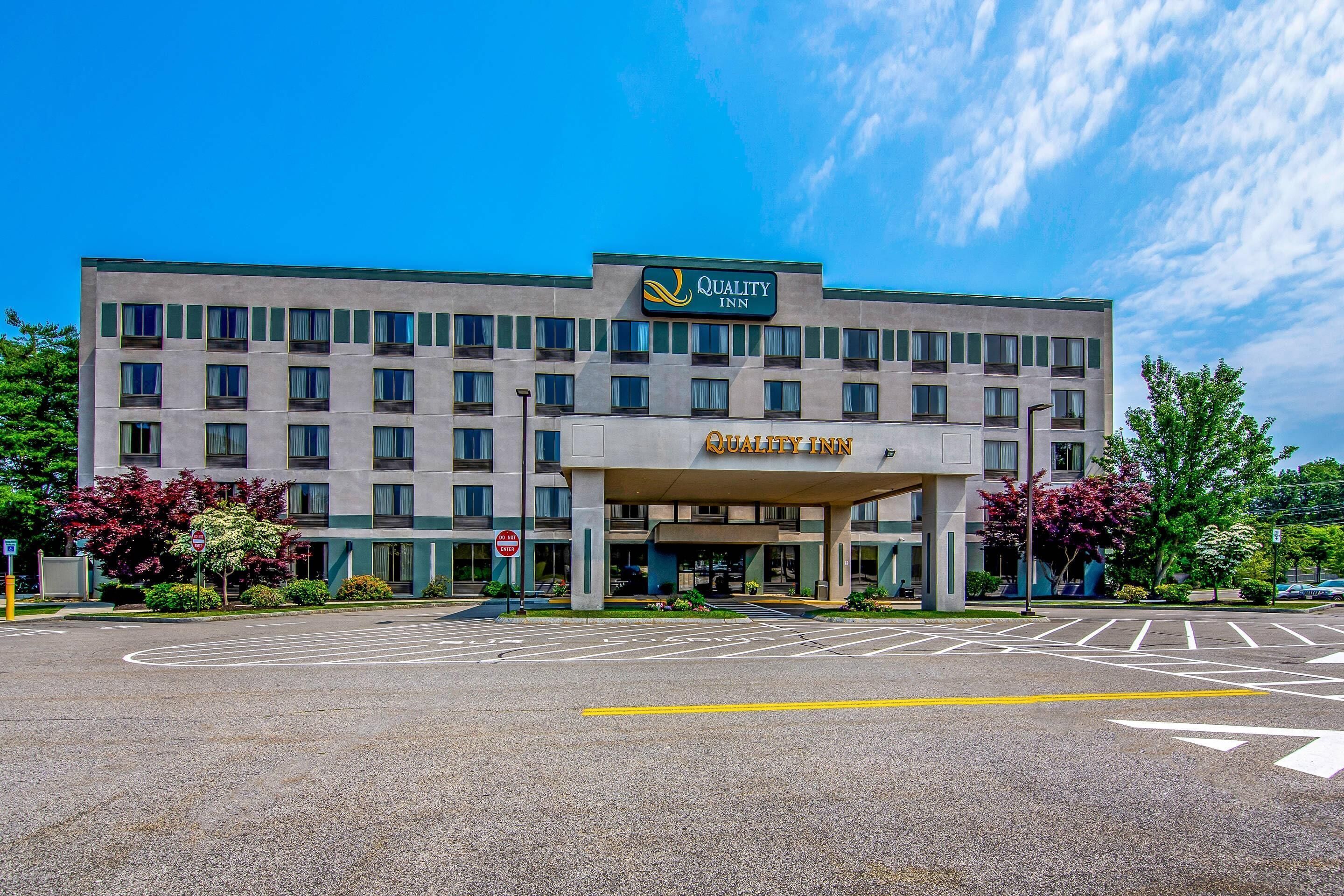 A Quality Inn hotel with a modern facade, multiple floors, and a clear sky.