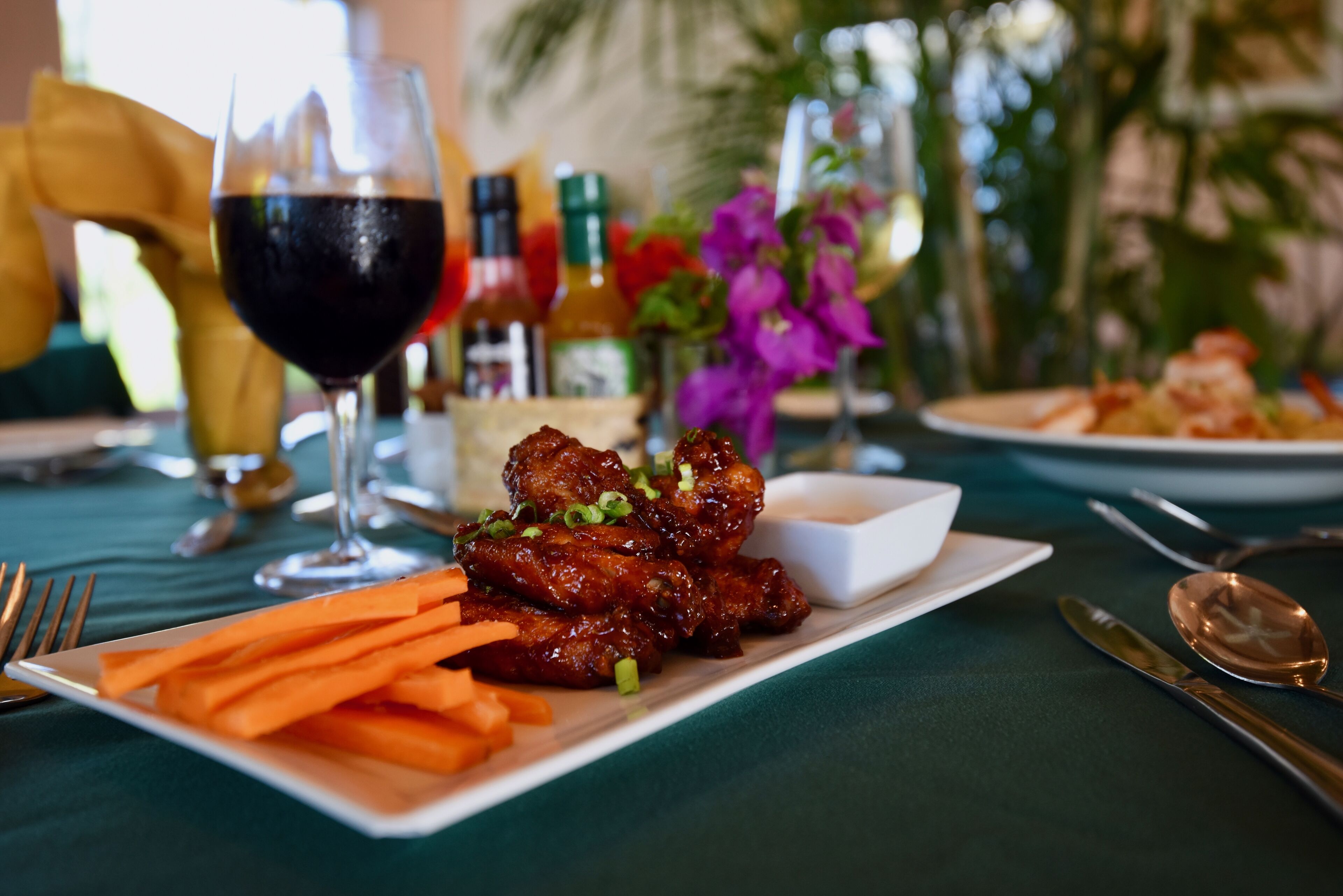 A dining table with a plate of food, a glass of red wine, and various condiments.