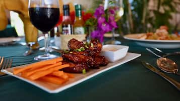A dining table with a plate of food, a glass of red wine, and various condiments.