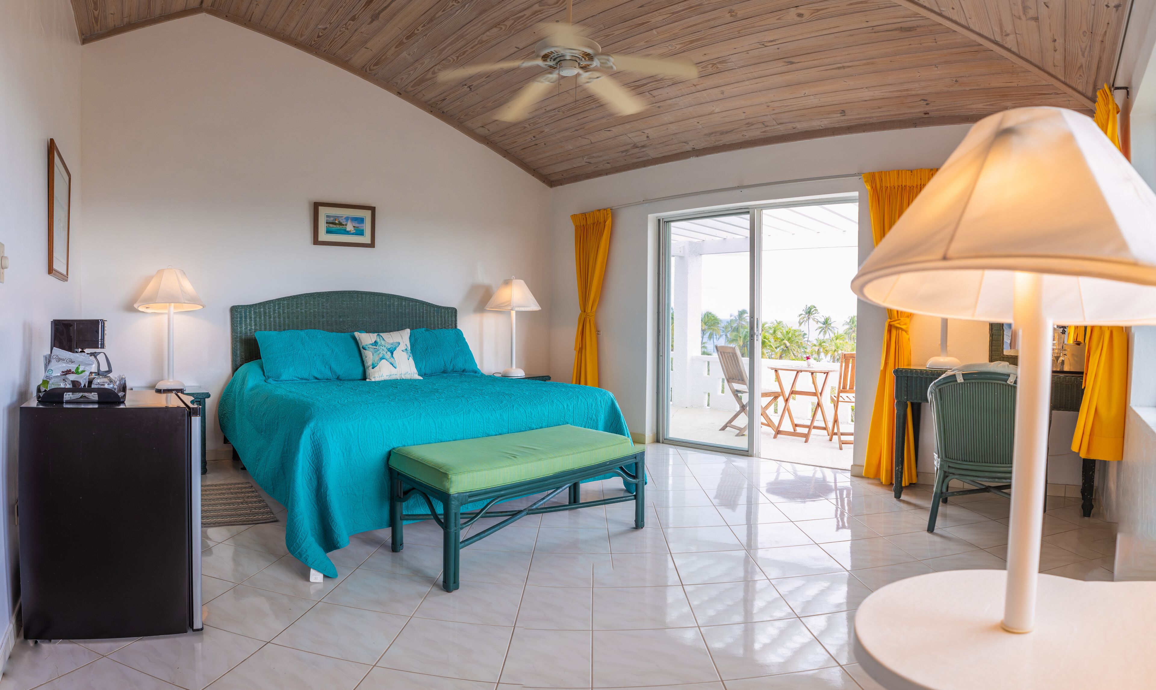 A bedroom with a bed, bedside tables, a desk, and a view of the outdoors.