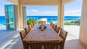 A wooden table with chairs on a balcony with a view of the ocean. - Stella Maris Resort Club (Stella Maris)
