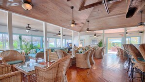 A spacious room with wicker furniture, wooden floors, and large windows. - Stella Maris Resort Club (Stella Maris)