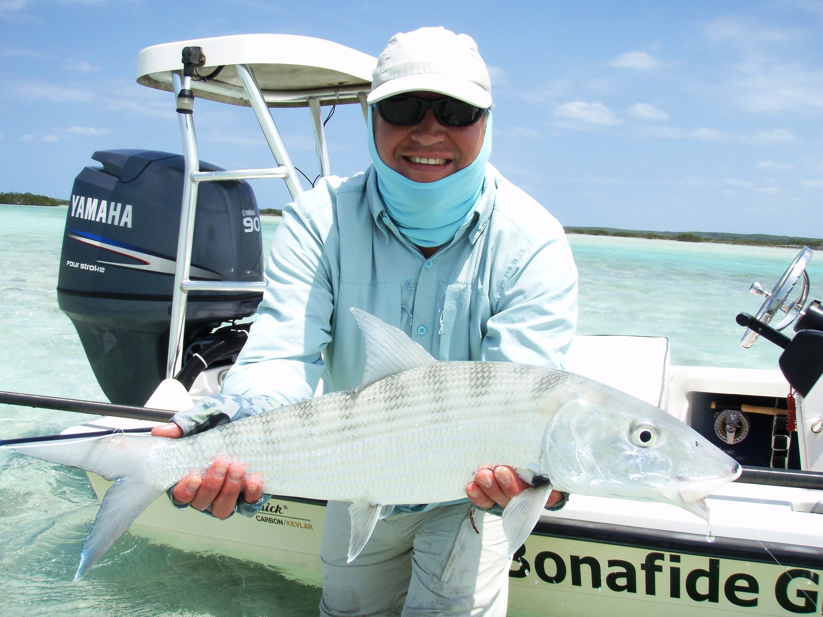A person holding a fish on a boat with a Yamaha outboard motor and a carbon/kevlar fishing rod.