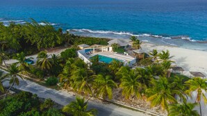 An aerial view of a beachfront property with a swimming pool, palm trees, and ocean views. - Stella Maris Resort Club (Stella Maris)
