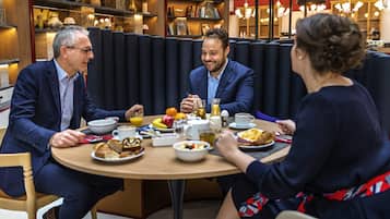 A group of people dining at a round table with various breakfast items.