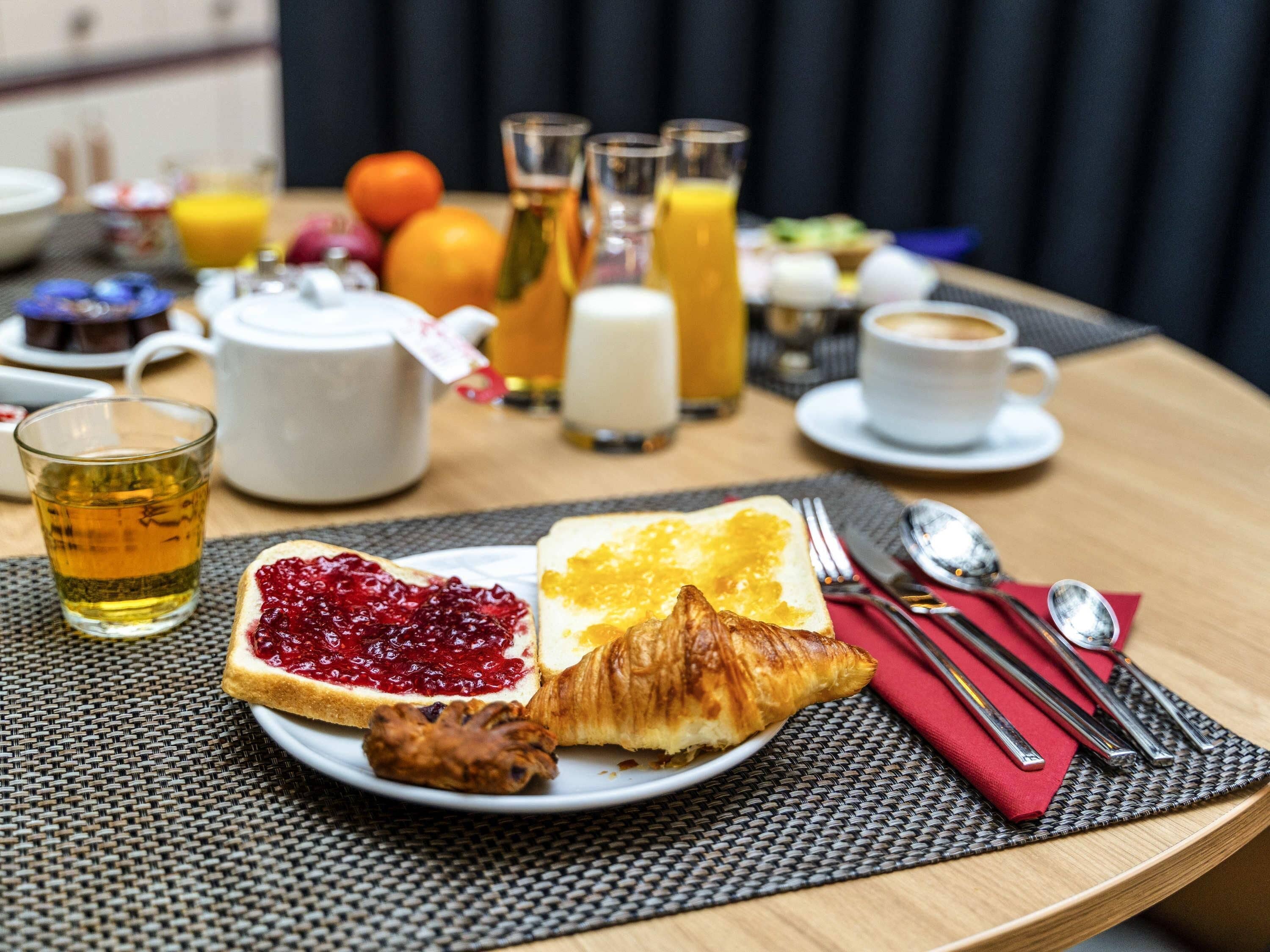 A breakfast setting with croissants, jam, and a glass of tea on a table.