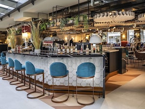 A modern bar area with a counter, bar stools, and potted plants.