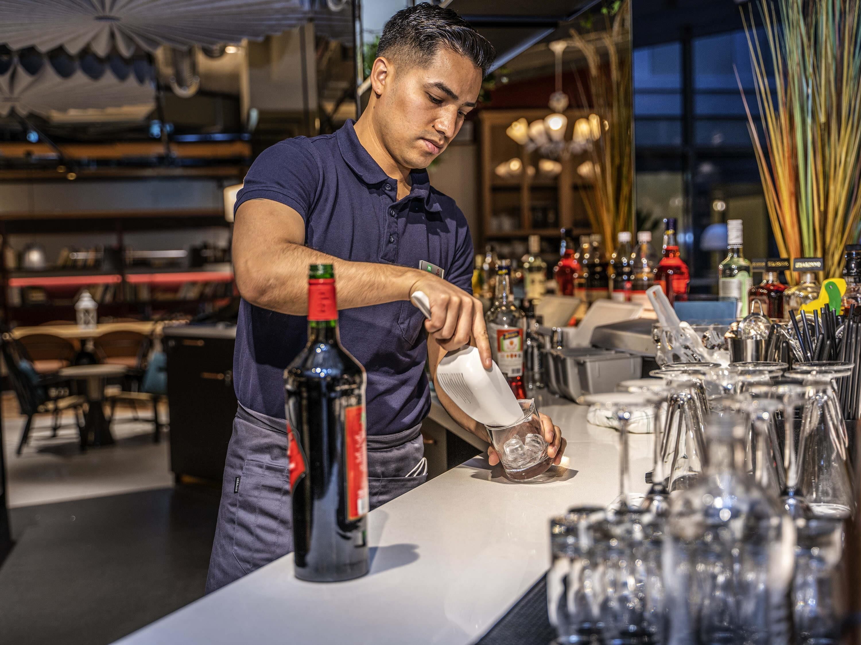 A bartender pouring a drink into a glass.