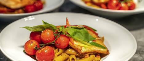 Tres platos de pasta con tomates cherry y albahaca sobre una mesa.
