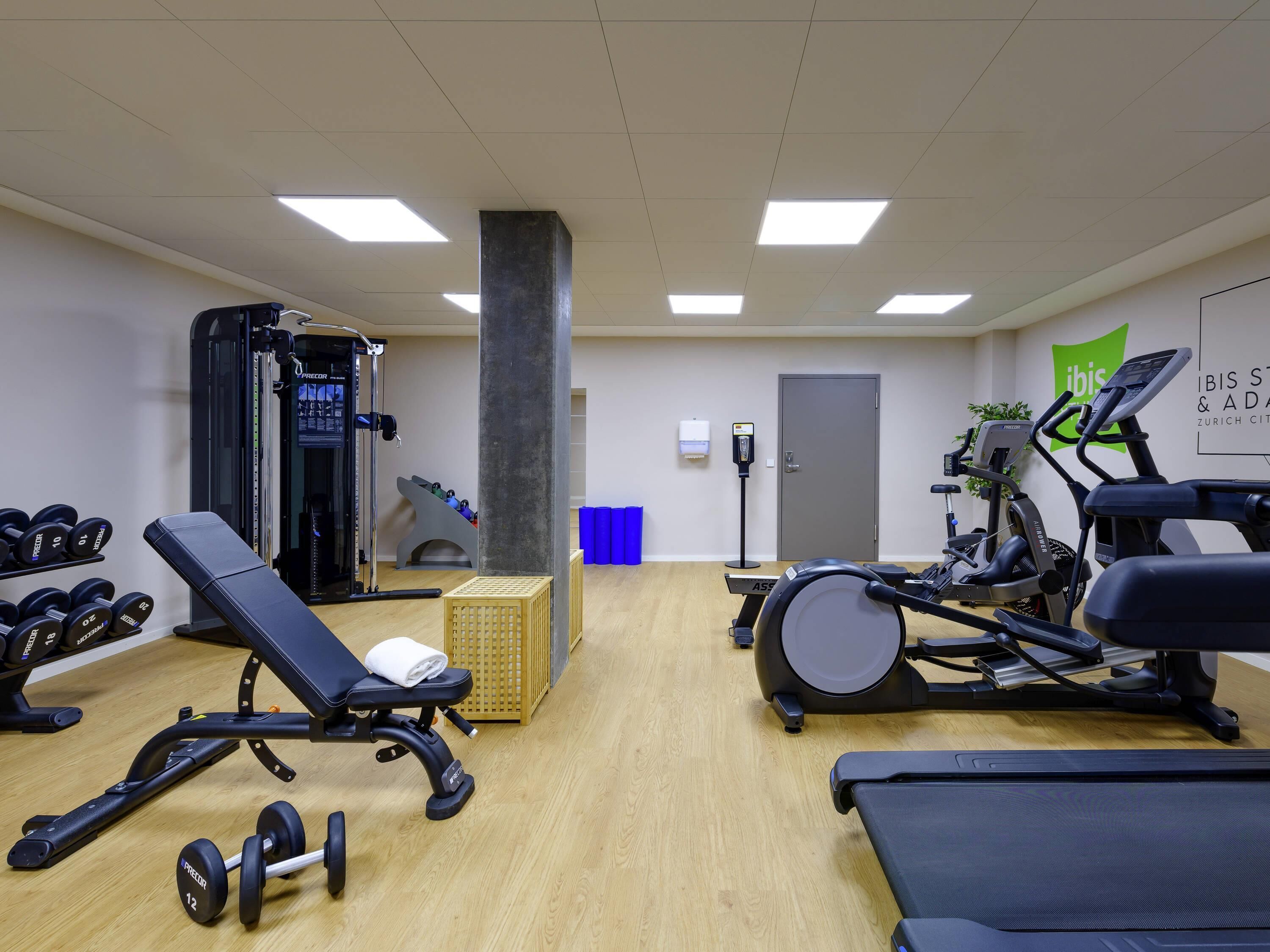 A gym with exercise equipment, a wall-mounted water dispenser, and a door.