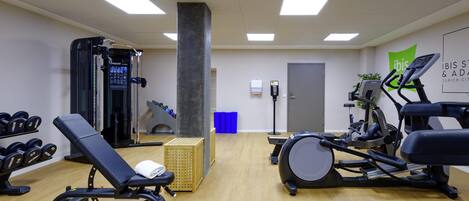 A gym with exercise equipment, a wall-mounted water dispenser, and a door.