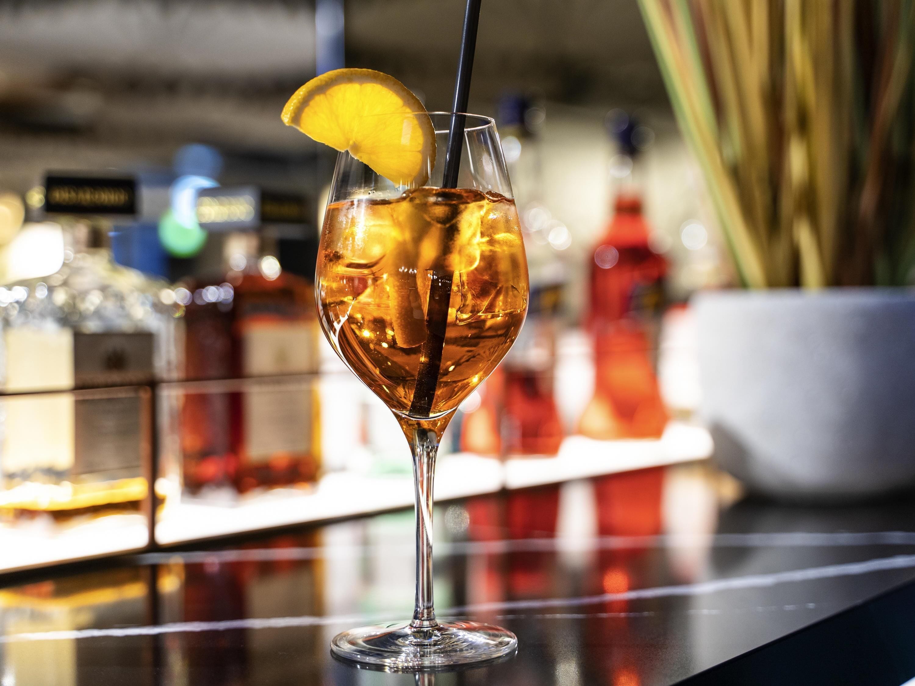 A cocktail glass with a lemon slice garnish on a bar counter.