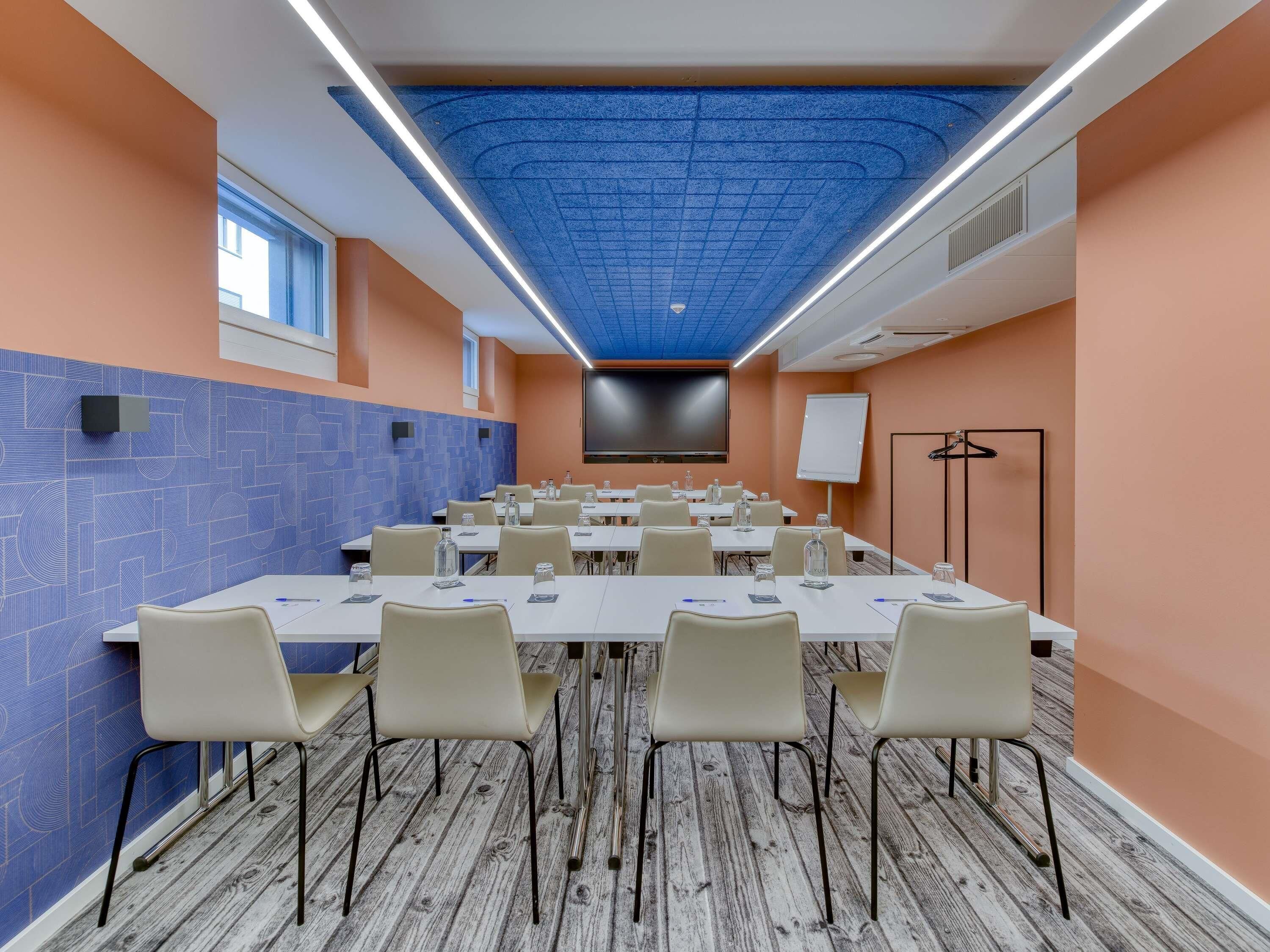 A conference room with a long table, chairs, a projector screen, and a whiteboard.
