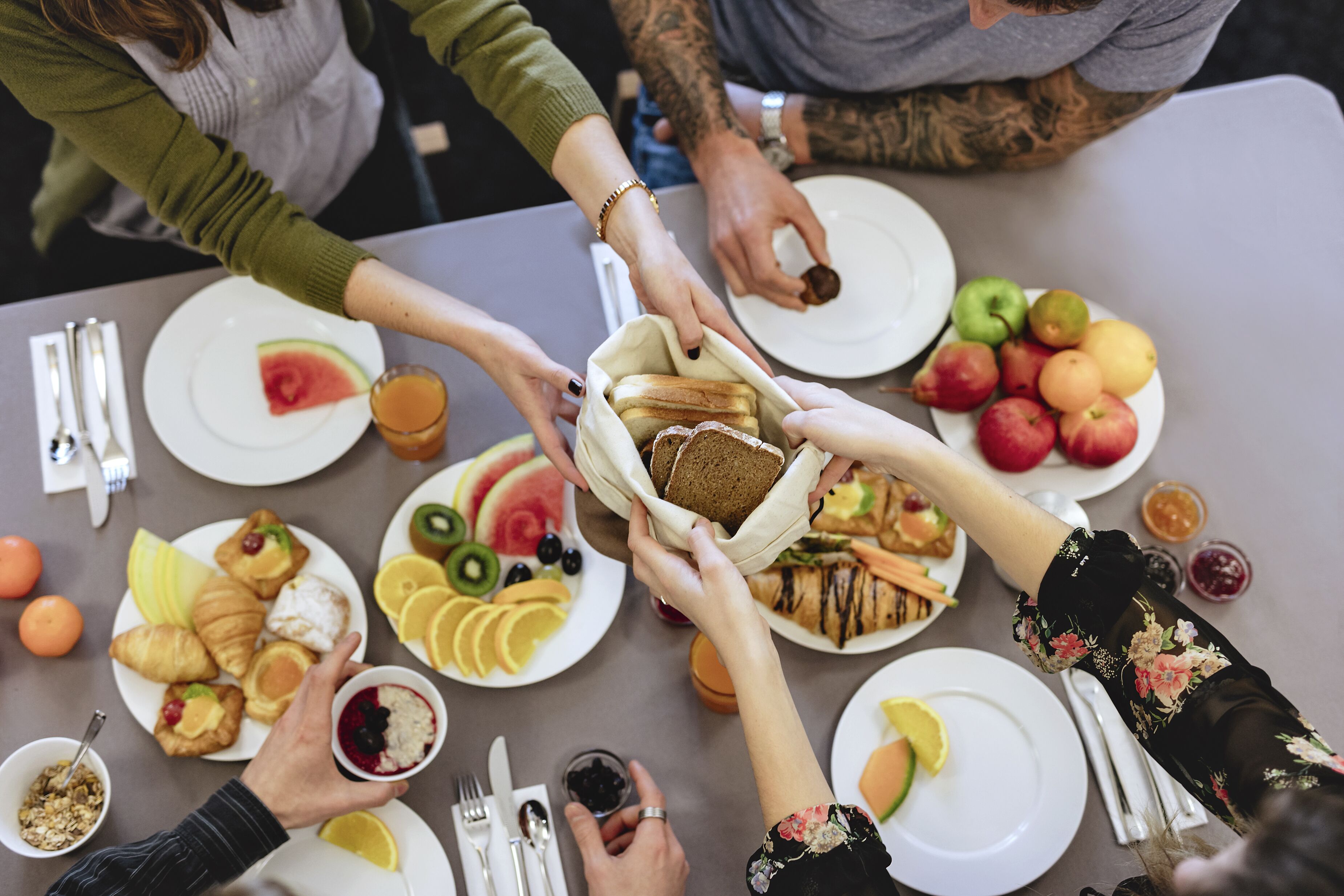 Un groupe de personnes partageant un repas autour d’une table, avec différents plats et des fruits.